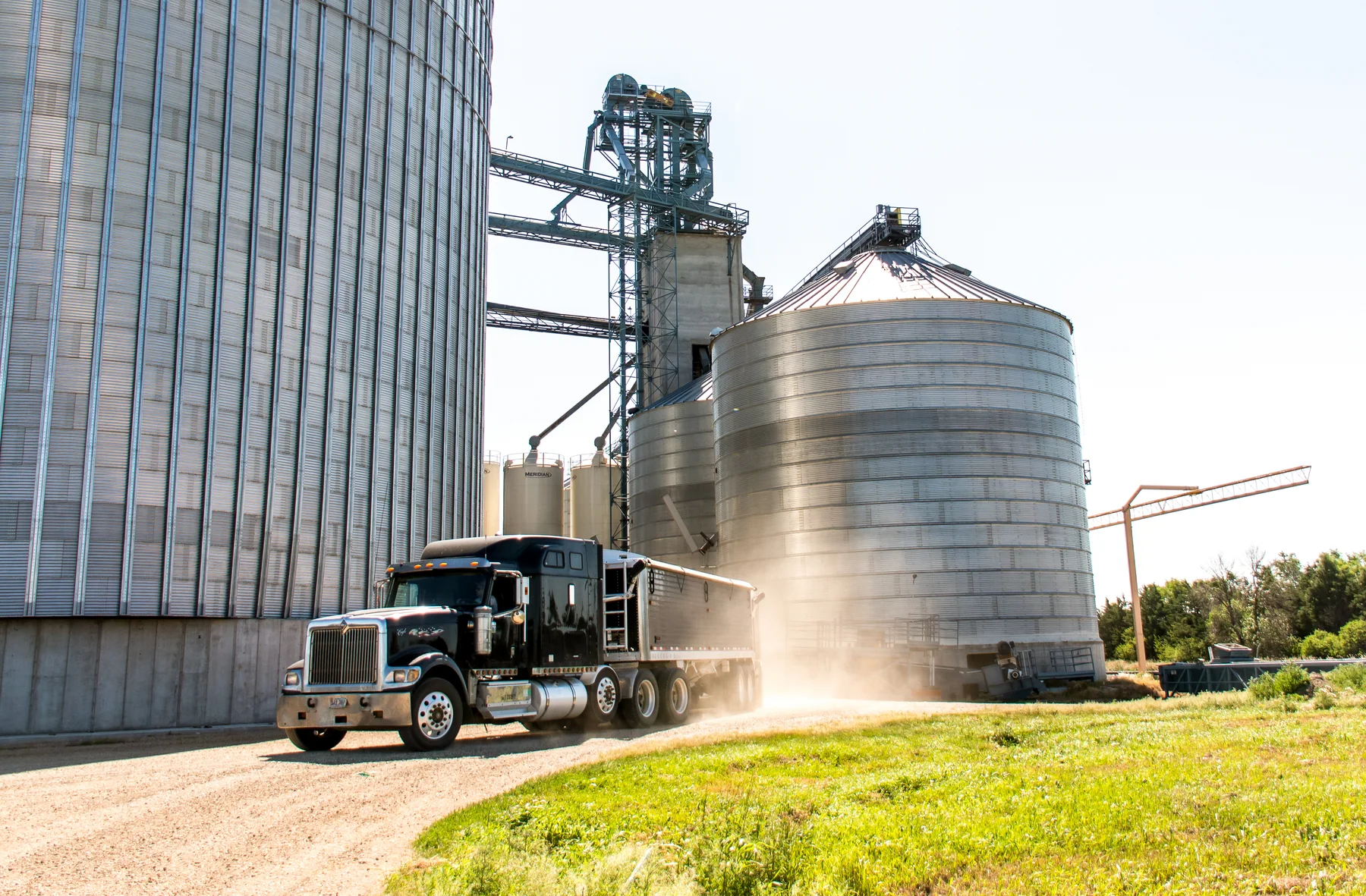 Grain truck moving through an operating grain facility with storage bins